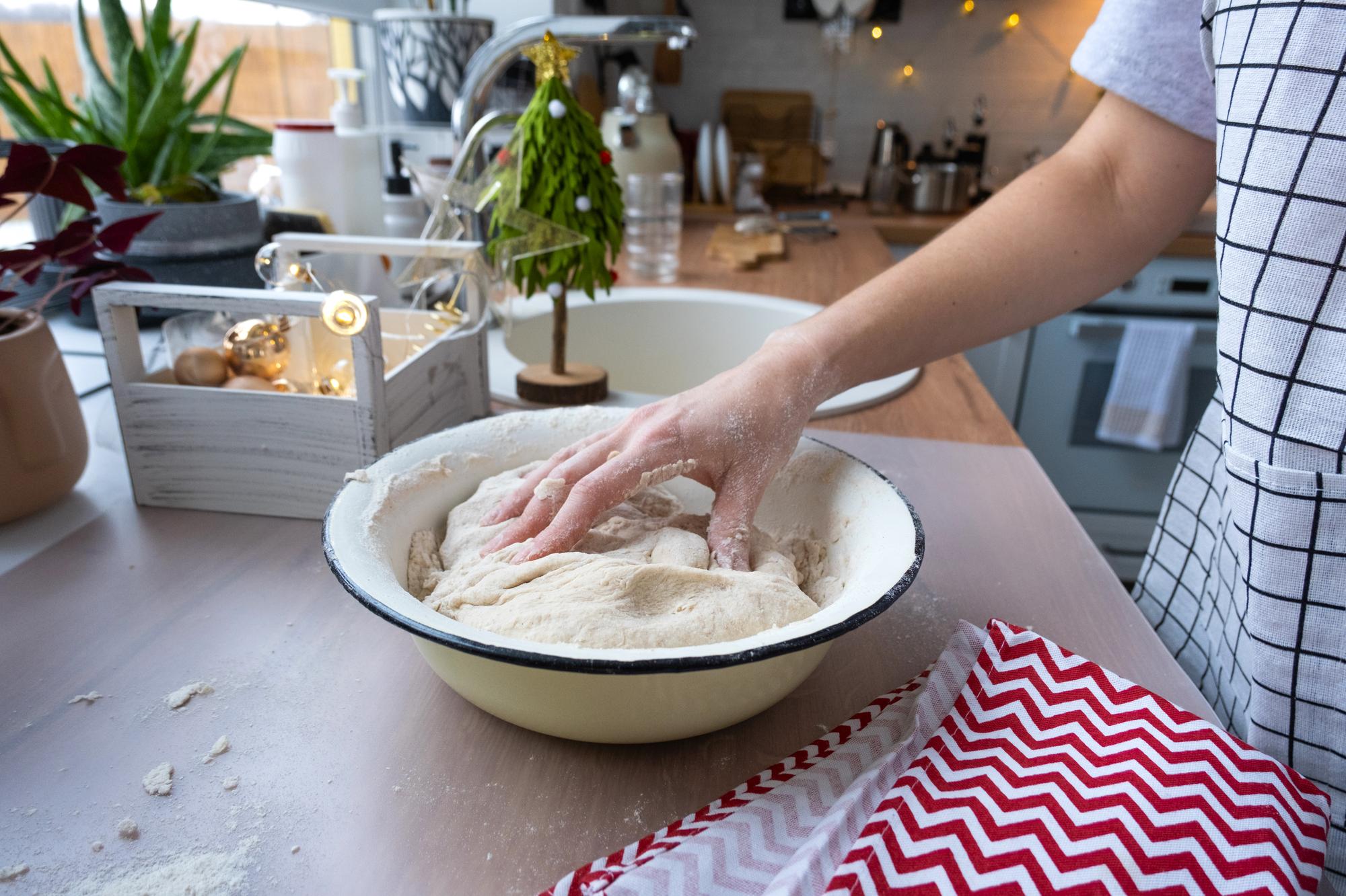 Hands kneading dough in modern kitchen